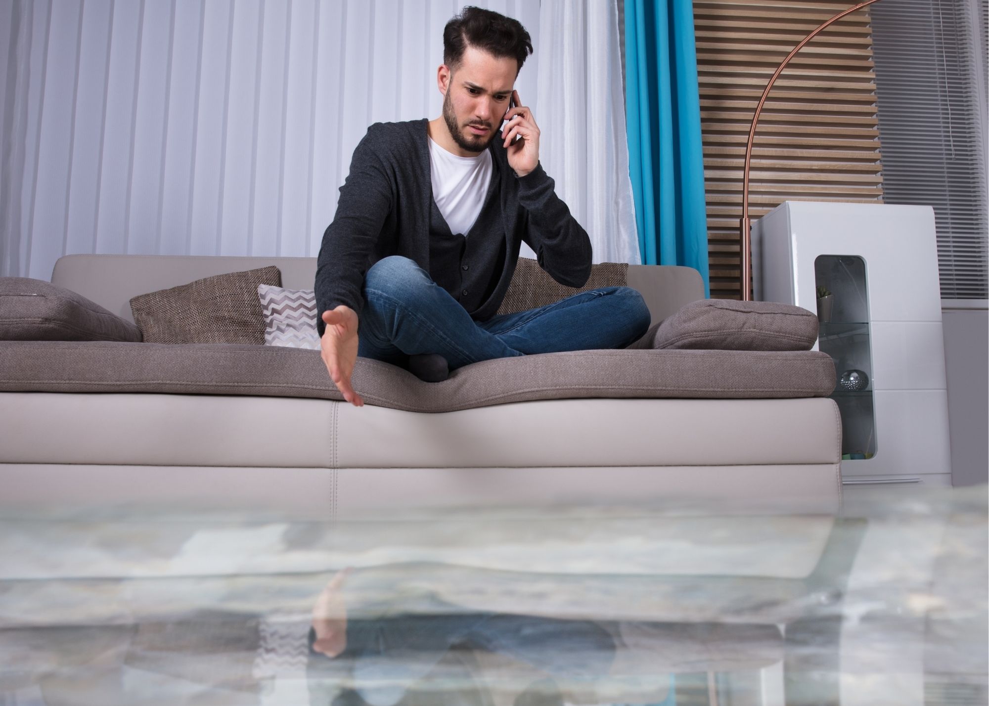 A homeowner calling for help beside water-damaged furniture in an Edgewater, FL home